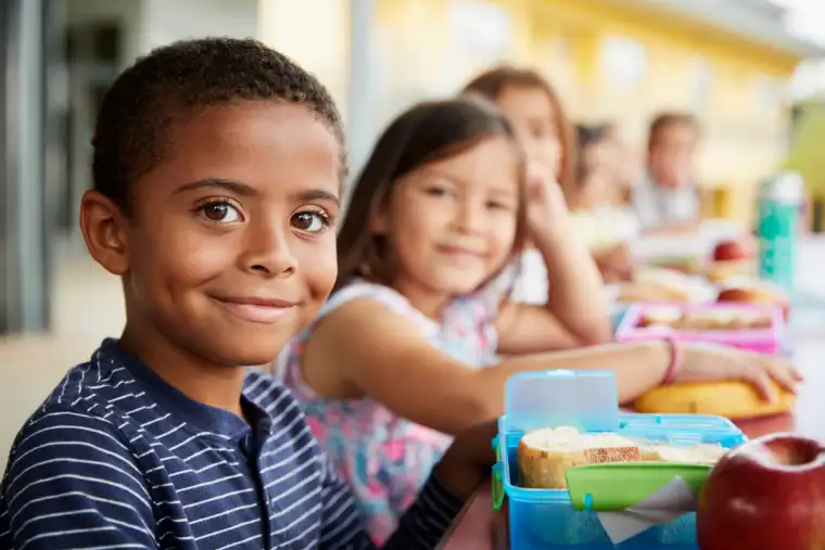 Young boy and girl at school lunch table smiling 