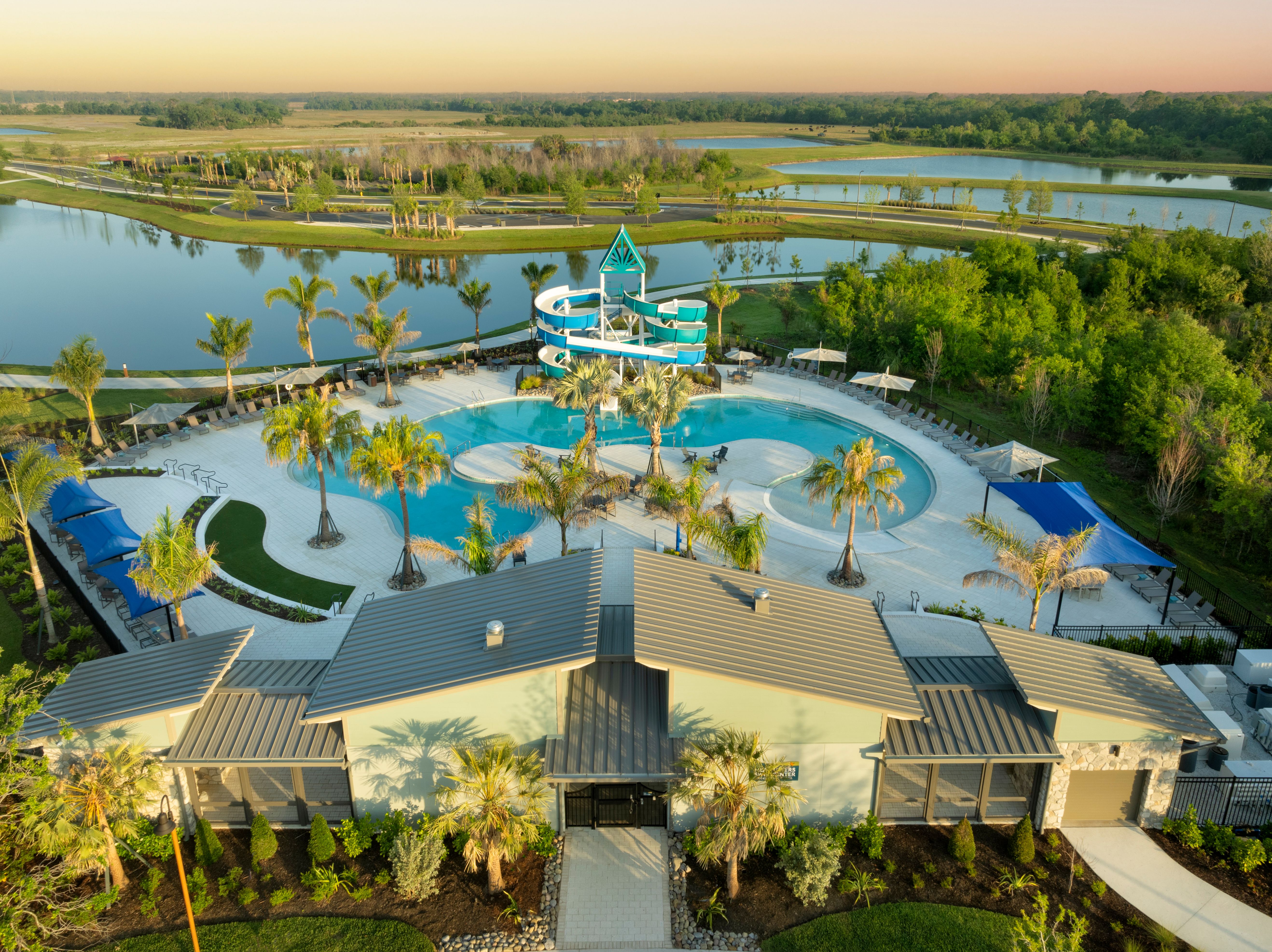 Aerial view of Camp Creek at North River Ranch featuring a resort-style pool with palm trees, cabanas, and a twisting water slide, surrounded by scenic lakes and lush greenery at sunset.​​​​‌﻿‍﻿​‍​‍‌‍﻿﻿‌﻿​‍‌‍‍‌‌‍‌﻿‌‍‍‌‌‍﻿‍​‍​‍​﻿‍‍​‍​‍‌﻿​﻿‌‍​‌‌‍﻿‍‌‍‍‌‌﻿‌​‌﻿‍‌​‍﻿‍‌‍‍‌‌‍﻿﻿​‍​‍​‍﻿​​‍​‍‌‍‍​‌﻿​‍‌‍‌‌‌‍‌‍​‍​‍​﻿‍‍​‍​‍​‍﻿﻿‌‍​‌‌‍‌​‌‍﻿‌‌‍‍‌‌‍﻿‍​‍﻿﻿‌﻿​﻿‌‍​‌‌‍﻿‍‌‍‍‌‌﻿‌​‌﻿‍‌​‍﻿﻿‌‍‍‌‌‍﻿‍‌﻿‌​‌‍‌‌‌‍﻿‍‌﻿‌​​‍﻿﻿‌‍‌‌‌‍‌​‌‍‍‌‌﻿‌​​‍﻿﻿‌‍﻿‌‌‍﻿﻿‌‍‌​‌‍‌‌​﻿﻿‌‌﻿​​‌﻿​‍‌‍‌‌‌﻿​﻿‌‍‌‌‌‍﻿‍‌﻿‌​‌‍​‌‌﻿‌​‌‍‍‌‌‍﻿﻿‌‍﻿‍​﻿‍﻿‌‍‍‌‌‍‌​​﻿﻿‌​﻿​​​﻿​‍​﻿‌​​﻿‌​​﻿‌‌​﻿‌​‌‍​‍​﻿‌﻿​‍﻿‌‌‍​‍‌‍​‌​﻿‍‌‌‍​‍​‍﻿‌​﻿‌​​﻿‌‍‌‍‌​​﻿‌‍​‍﻿‌‌‍​‍​﻿‍​​﻿​​​﻿‌​​‍﻿‌​﻿‌‍‌‍​‌​﻿‍‌‌‍​‌​﻿‍​​﻿‌‌‌‍​﻿‌‍​﻿​﻿‌‌‌‍​﻿‌‍‌‍​﻿​﻿​﻿‍﻿‌﻿‌​‌﻿‍‌‌﻿​​‌‍‌‌​﻿﻿‌‌‍﻿‍‌‍‌‌‌﻿‌﻿‌﻿​﻿‌‌​​‌‍﻿﻿‌﻿​﻿‌﻿‌​​﻿‍﻿‌﻿​​‌‍​‌‌﻿‌​‌‍‍​​﻿﻿‌‌‍﻿‌‌‍​‌‌‍‍‌‌‍﻿‍‌​‍‌‌‍﻿‌‌‍​‌‌‍‌﻿‌‍‌‌​‍﻿‍‌‍​‌‌‍﻿​‌﻿‌​​﻿﻿﻿‌‍​‍‌‍​‌‌﻿​﻿‌‍‌‌‌‌‌‌‌﻿​‍‌‍﻿​​﻿﻿‌​‍‌‌​﻿​‍‌​‌‍‌‍​‌‌‍‌​‌‍﻿‌‌‍‍‌‌‍﻿‍​‍‌‌​﻿​‍‌​‌‍‌﻿​﻿‌‍​‌‌‍﻿‍‌‍‍‌‌﻿‌​‌﻿‍‌​‍‌‍‌‍‍‌‌‍‌​​﻿﻿‌​﻿​​​﻿​‍​﻿‌​​﻿‌​​﻿‌‌​﻿‌​‌‍​‍​﻿‌﻿​‍﻿‌‌‍​‍‌‍​‌​﻿‍‌‌‍​‍​‍﻿‌​﻿‌​​﻿‌‍‌‍‌​​﻿‌‍​‍﻿‌‌‍​‍​﻿‍​​﻿​​​﻿‌​​‍﻿‌​﻿‌‍‌‍​‌​﻿‍‌‌‍​‌​﻿‍​​﻿‌‌‌‍​﻿‌‍​﻿​﻿‌‌‌‍​﻿‌‍‌‍​﻿​﻿​‍‌‍‌﻿‌​‌﻿‍‌‌﻿​​‌‍‌‌​﻿﻿‌‌‍﻿‍‌‍‌‌‌﻿‌﻿‌﻿​﻿‌‌​​‌‍﻿﻿‌﻿​﻿‌﻿‌​​‍‌‍‌﻿​​‌‍​‌‌﻿‌​‌‍‍​​﻿﻿‌‌‍﻿‌‌‍​‌‌‍‍‌‌‍﻿‍‌​‍‌‌‍﻿‌‌‍​‌‌‍‌﻿‌‍‌‌​‍﻿‍‌‍​‌‌‍﻿​‌﻿‌​​‍‌‍‌﻿​​‌‍‌‌‌﻿​‍‌﻿​﻿‌﻿​​‌‍‌‌‌‍​﻿‌﻿‌​‌‍‍‌‌﻿‌‍‌‍‌‌​﻿﻿‌‌﻿​​‌﻿‌‌‌‍​‍‌‍﻿​‌‍‍‌‌﻿​﻿‌‍‍​‌‍‌‌‌‍‌​​‍​‍‌﻿﻿‌