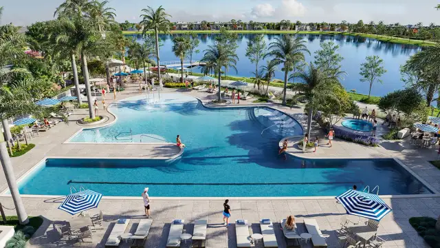 Resort style community pool at SeaFlower in Parrish, Florida, overlooking a lake with palm trees, lounge seating, and residents enjoying outdoor amenities.