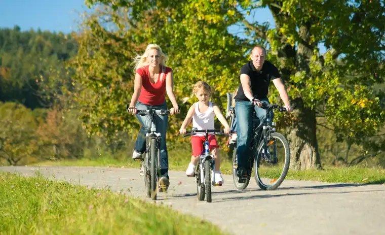 Family riding bikes together on a paved pathway in Calgary.