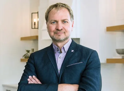 Richard Bukarewicz wearing a suit is positioned in a contemporary kitchen.