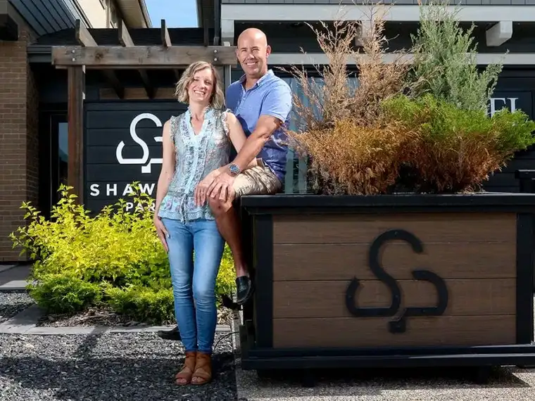 A man and woman stand side by side, smiling for a photo in front of the Shawnee Park showhome