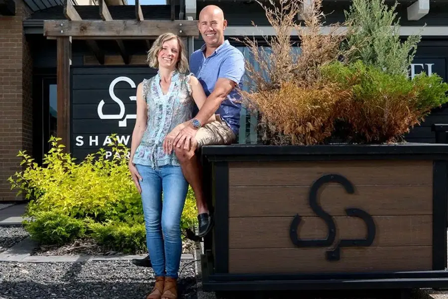 A man and woman stand side by side, smiling for a photo in front of the Shawnee Park showhome