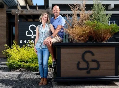A man and woman stand side by side, smiling for a photo in front of the Shawnee Park showhome