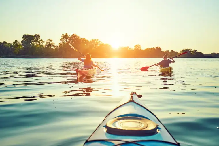 Three people kayaking on a lake at sunset in Florida.