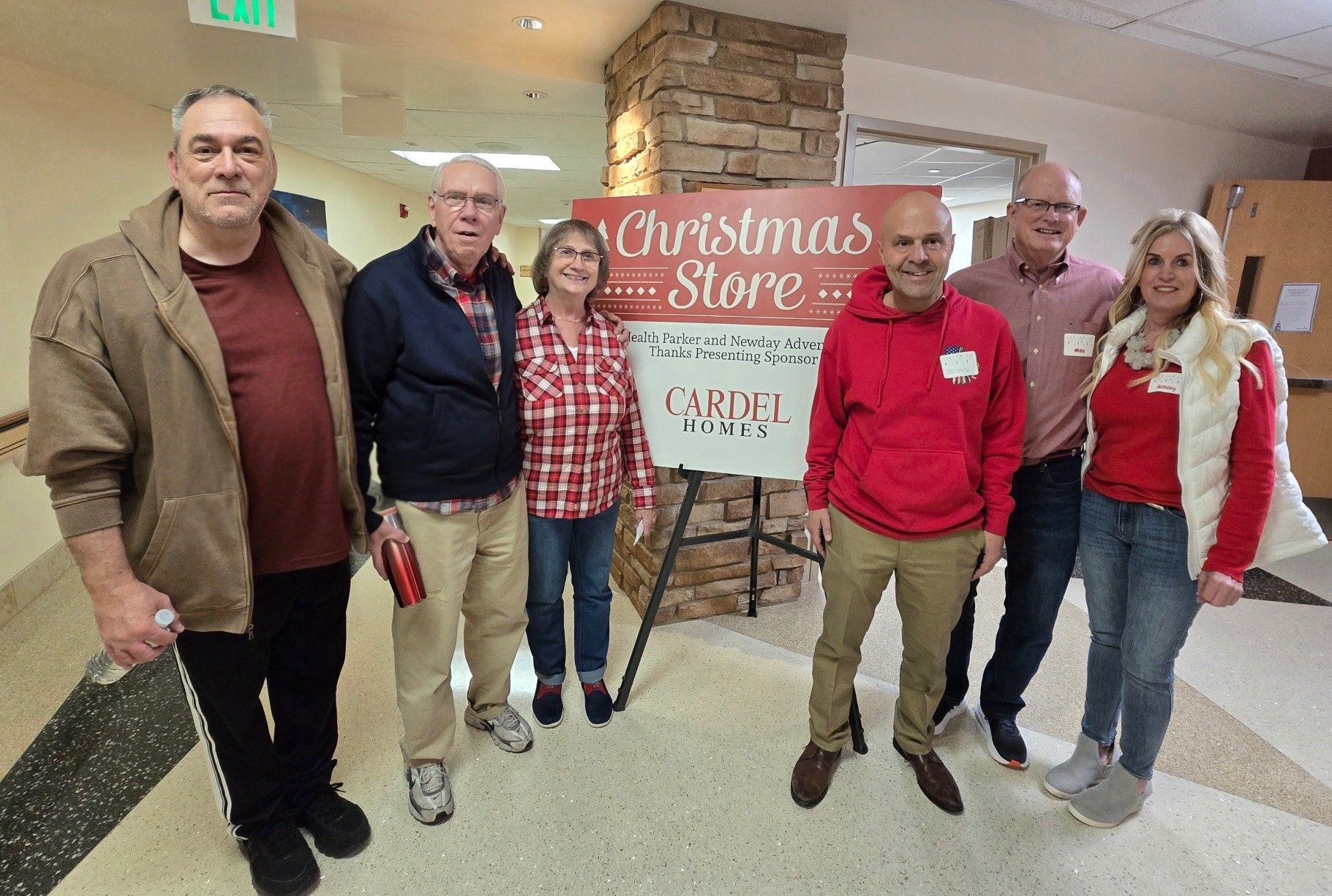 Cardel Homes team members and volunteers standing beside the AdventHealth Parker Christmas Store sign at the hospital.​​​​‌﻿‍﻿​‍​‍‌‍﻿﻿‌﻿​‍‌‍‍‌‌‍‌﻿‌‍‍‌‌‍﻿‍​‍​‍​﻿‍‍​‍​‍‌﻿​﻿‌‍​‌‌‍﻿‍‌‍‍‌‌﻿‌​‌﻿‍‌​‍﻿‍‌‍‍‌‌‍﻿﻿​‍​‍​‍﻿​​‍​‍‌‍‍​‌﻿​‍‌‍‌‌‌‍‌‍​‍​‍​﻿‍‍​‍​‍​‍﻿﻿‌‍​‌‌‍‌​‌‍﻿‌‌‍‍‌‌‍﻿‍​‍﻿﻿‌﻿​﻿‌‍​‌‌‍﻿‍‌‍‍‌‌﻿‌​‌﻿‍‌​‍﻿﻿‌‍‍‌‌‍﻿‍‌﻿‌​‌‍‌‌‌‍﻿‍‌﻿‌​​‍﻿﻿‌‍‌‌‌‍‌​‌‍‍‌‌﻿‌​​‍﻿﻿‌‍﻿‌‌‍﻿﻿‌‍‌​‌‍‌‌​﻿﻿‌‌﻿​​‌﻿​‍‌‍‌‌‌﻿​﻿‌‍‌‌‌‍﻿‍‌﻿‌​‌‍​‌‌﻿‌​‌‍‍‌‌‍﻿﻿‌‍﻿‍​﻿‍﻿‌‍‍‌‌‍‌​​﻿﻿‌​﻿​﻿​﻿​﻿​﻿​‌‌‍‌​​﻿​‍‌‍‌‍​﻿​‍‌‍‌‌​‍﻿‌​﻿​﻿‌‍​﻿​﻿‌﻿‌‍​‌​‍﻿‌​﻿‌​​﻿​﻿‌‍​‍​﻿​﻿​‍﻿‌‌‍​‌​﻿​‌‌‍‌‌​﻿​​​‍﻿‌​﻿​‌‌‍​‍‌‍‌‌​﻿​​​﻿‍​‌‍‌‌‌‍‌​​﻿‌‍​﻿‌﻿‌‍​‍‌‍​‌​﻿​​​﻿‍﻿‌﻿‌​‌﻿‍‌‌﻿​​‌‍‌‌​﻿﻿‌‌‍﻿‍‌‍‌‌‌﻿‌﻿‌﻿​﻿‌‌​​‌‍﻿﻿‌﻿​﻿‌﻿‌​​﻿‍﻿‌﻿​​‌‍​‌‌﻿‌​‌‍‍​​﻿﻿‌‌‍﻿‌‌‍​‌‌‍‍‌‌‍﻿‍‌​‍‌‌‍﻿‌‌‍​‌‌‍‌﻿‌‍‌‌​‍﻿‍‌‍​‌‌‍﻿​‌﻿‌​​﻿﻿﻿‌‍​‍‌‍​‌‌﻿​﻿‌‍‌‌‌‌‌‌‌﻿​‍‌‍﻿​​﻿﻿‌​‍‌‌​﻿​‍‌​‌‍‌‍​‌‌‍‌​‌‍﻿‌‌‍‍‌‌‍﻿‍​‍‌‌​﻿​‍‌​‌‍‌﻿​﻿‌‍​‌‌‍﻿‍‌‍‍‌‌﻿‌​‌﻿‍‌​‍‌‍‌‍‍‌‌‍‌​​﻿﻿‌​﻿​﻿​﻿​﻿​﻿​‌‌‍‌​​﻿​‍‌‍‌‍​﻿​‍‌‍‌‌​‍﻿‌​﻿​﻿‌‍​﻿​﻿‌﻿‌‍​‌​‍﻿‌​﻿‌​​﻿​﻿‌‍​‍​﻿​﻿​‍﻿‌‌‍​‌​﻿​‌‌‍‌‌​﻿​​​‍﻿‌​﻿​‌‌‍​‍‌‍‌‌​﻿​​​﻿‍​‌‍‌‌‌‍‌​​﻿‌‍​﻿‌﻿‌‍​‍‌‍​‌​﻿​​​‍‌‍‌﻿‌​‌﻿‍‌‌﻿​​‌‍‌‌​﻿﻿‌‌‍﻿‍‌‍‌‌‌﻿‌﻿‌﻿​﻿‌‌​​‌‍﻿﻿‌﻿​﻿‌﻿‌​​‍‌‍‌﻿​​‌‍​‌‌﻿‌​‌‍‍​​﻿﻿‌‌‍﻿‌‌‍​‌‌‍‍‌‌‍﻿‍‌​‍‌‌‍﻿‌‌‍​‌‌‍‌﻿‌‍‌‌​‍﻿‍‌‍​‌‌‍﻿​‌﻿‌​​‍‌‍‌﻿​​‌‍‌‌‌﻿​‍‌﻿​﻿‌﻿​​‌‍‌‌‌‍​﻿‌﻿‌​‌‍‍‌‌﻿‌‍‌‍‌‌​﻿﻿‌‌﻿​​‌﻿‌‌‌‍​‍‌‍﻿​‌‍‍‌‌﻿​﻿‌‍‍​‌‍‌‌‌‍‌​​‍​‍‌﻿﻿‌