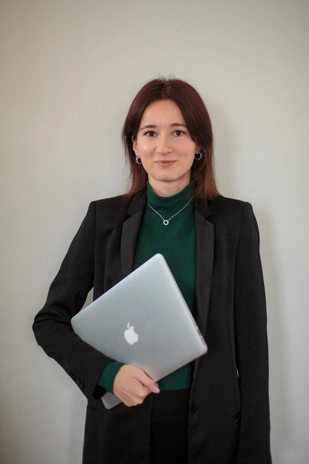 Maša Bujić drži laptop i stoji ispred svetlog zida
