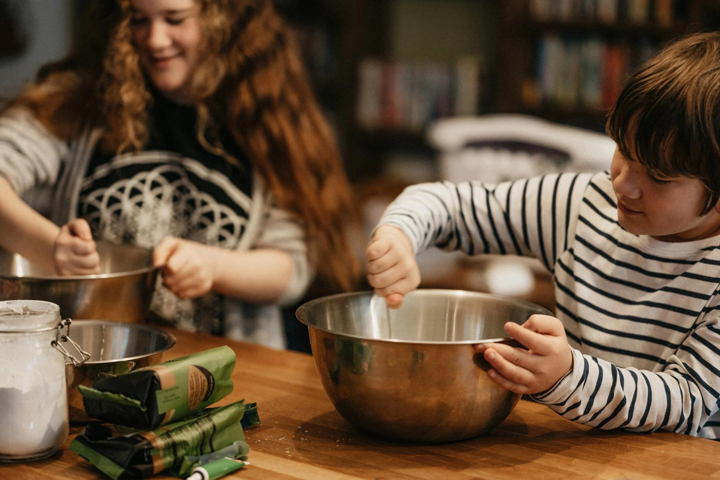 Two kids mixing ingredients at a kitchen table