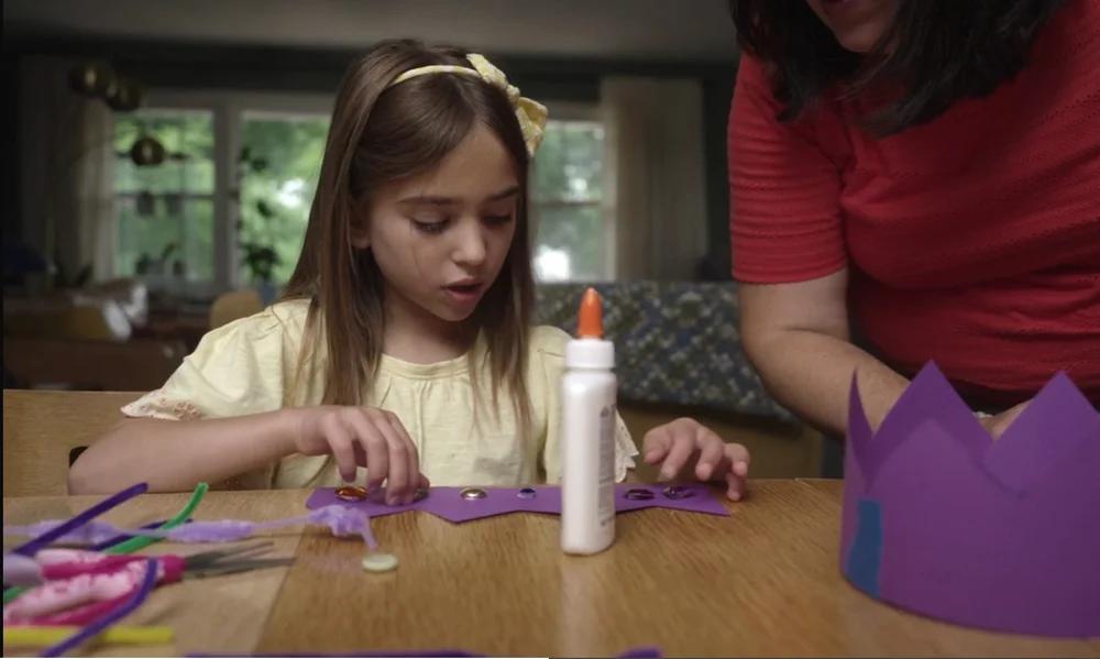 A girl glueing embellishments on a paper crown