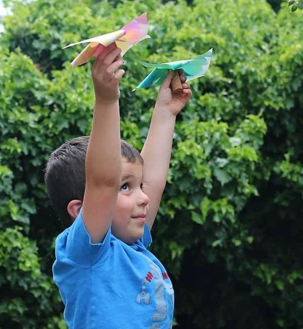 A boy holds two paper pinwheels