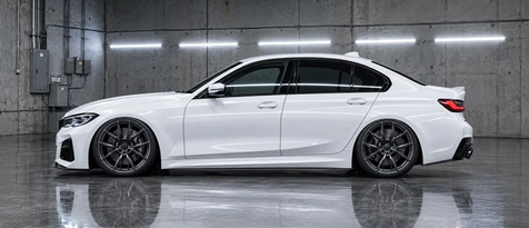 Custom gloss liquid smoke wheels paired with a dialed suspension ride height on an alpine white sedan in Houston, TX. Precision stance tuning and flush fender fitment.