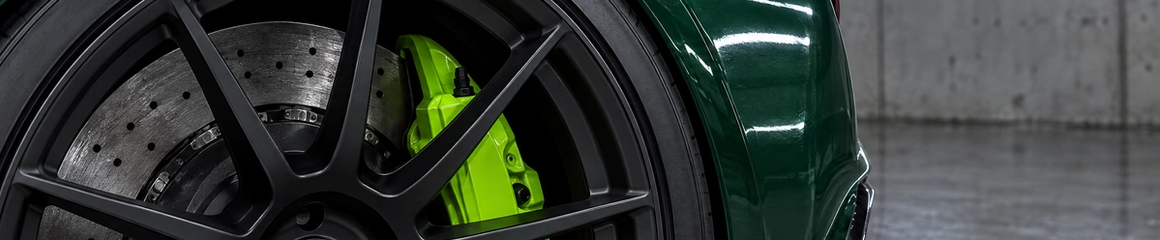 * Precision millimeter-precise wheel fitment featuring matte black monoblock wheels and vivid colored brake calipers on a British Racing Green sports car in Houston, Texas.