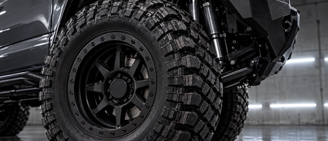 Aggressive lifted truck stance featuring mud-terrain tires, beadlock-style wheels, and upgraded off-road suspension. Precision wheel fitment paired with premium shocks from industry leaders like Fox, King Shocks, and Icon Vehicle Dynamics.