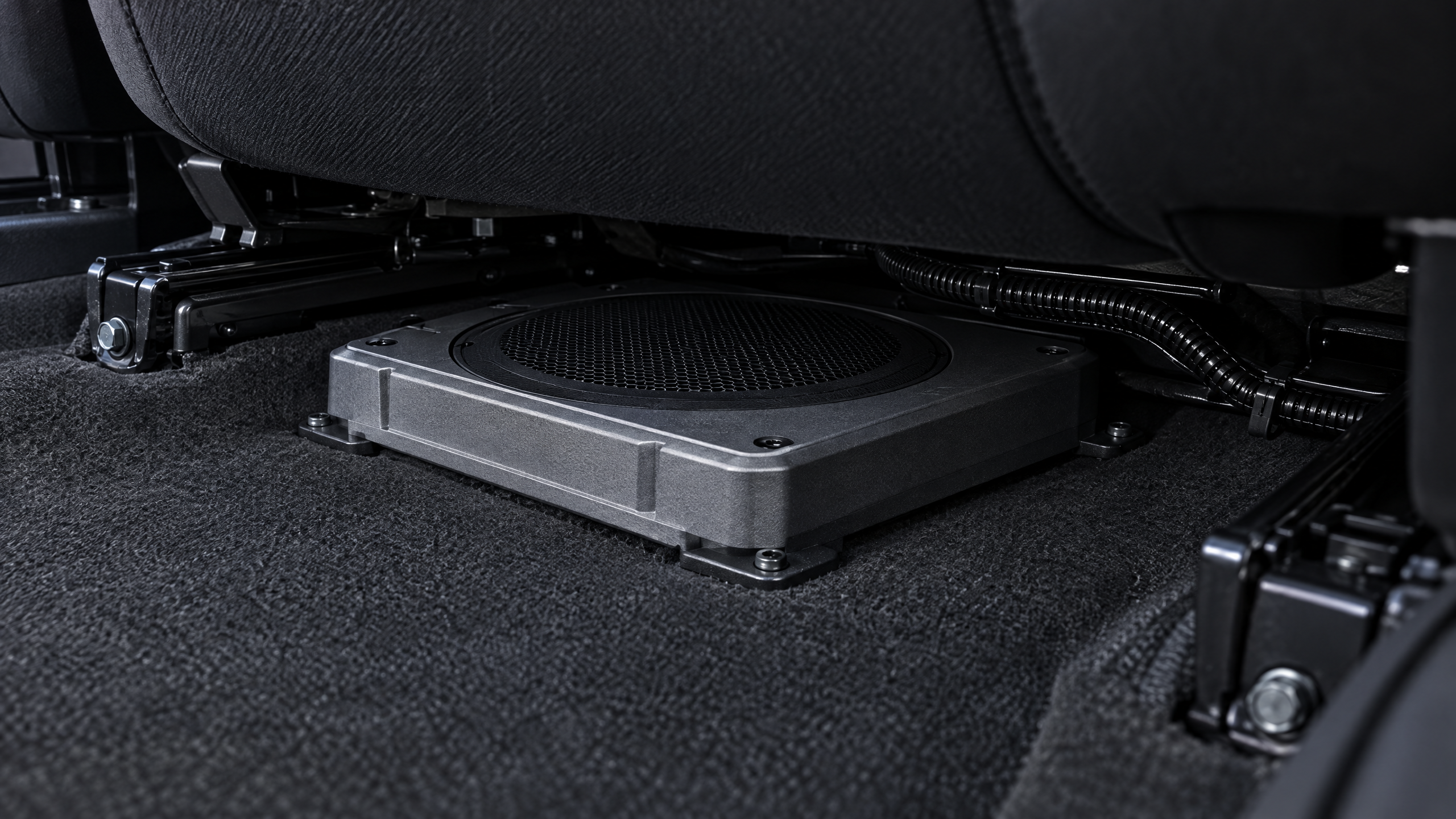 Stealth under-seat powered subwoofer and compact car audio installation in Houston. Hidden amplifier and subwoofer mounting for trucks, EVs, and sports cars seeking space-saving audio upgrades.