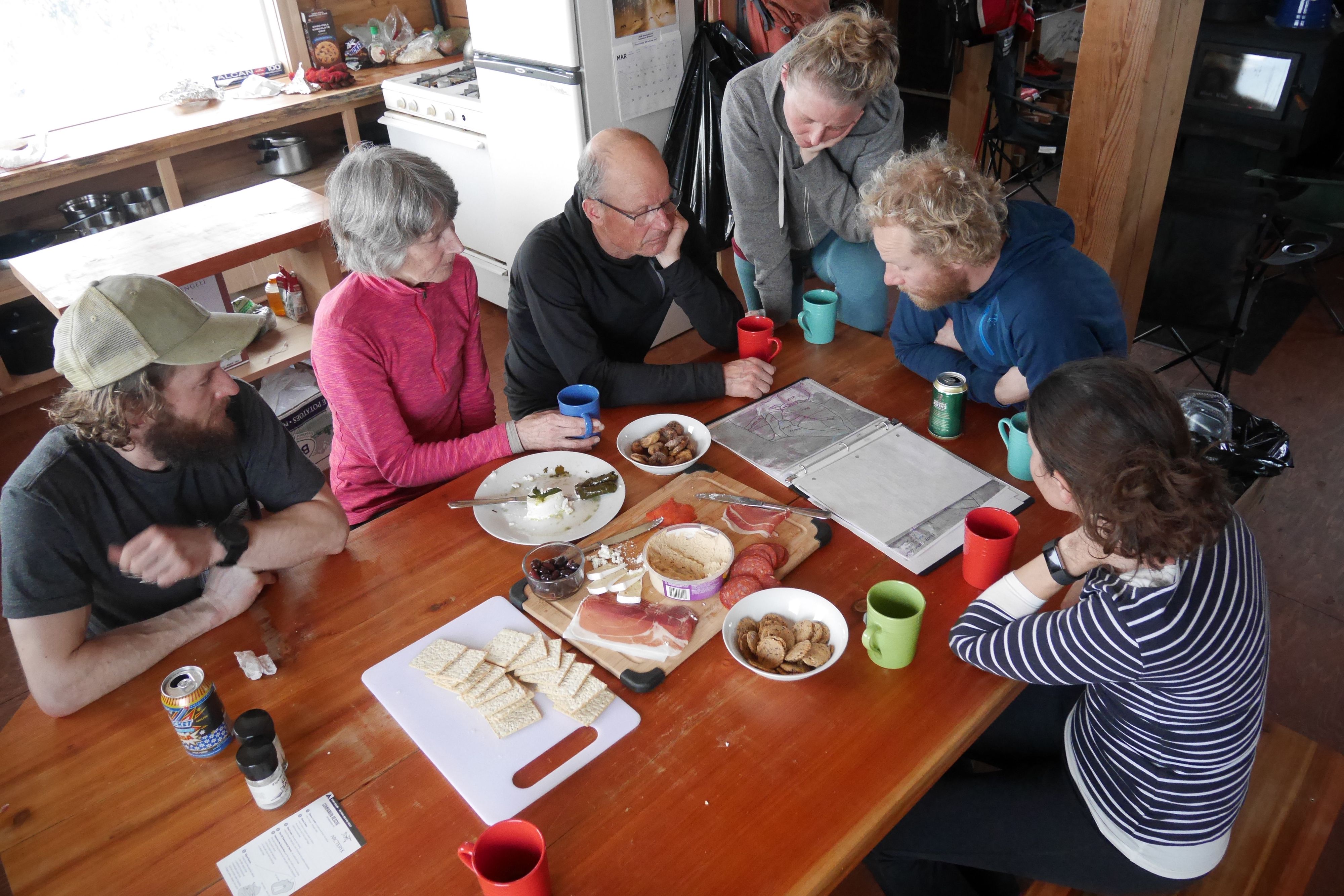 Six people sitting around a table in a backcountry lodge.