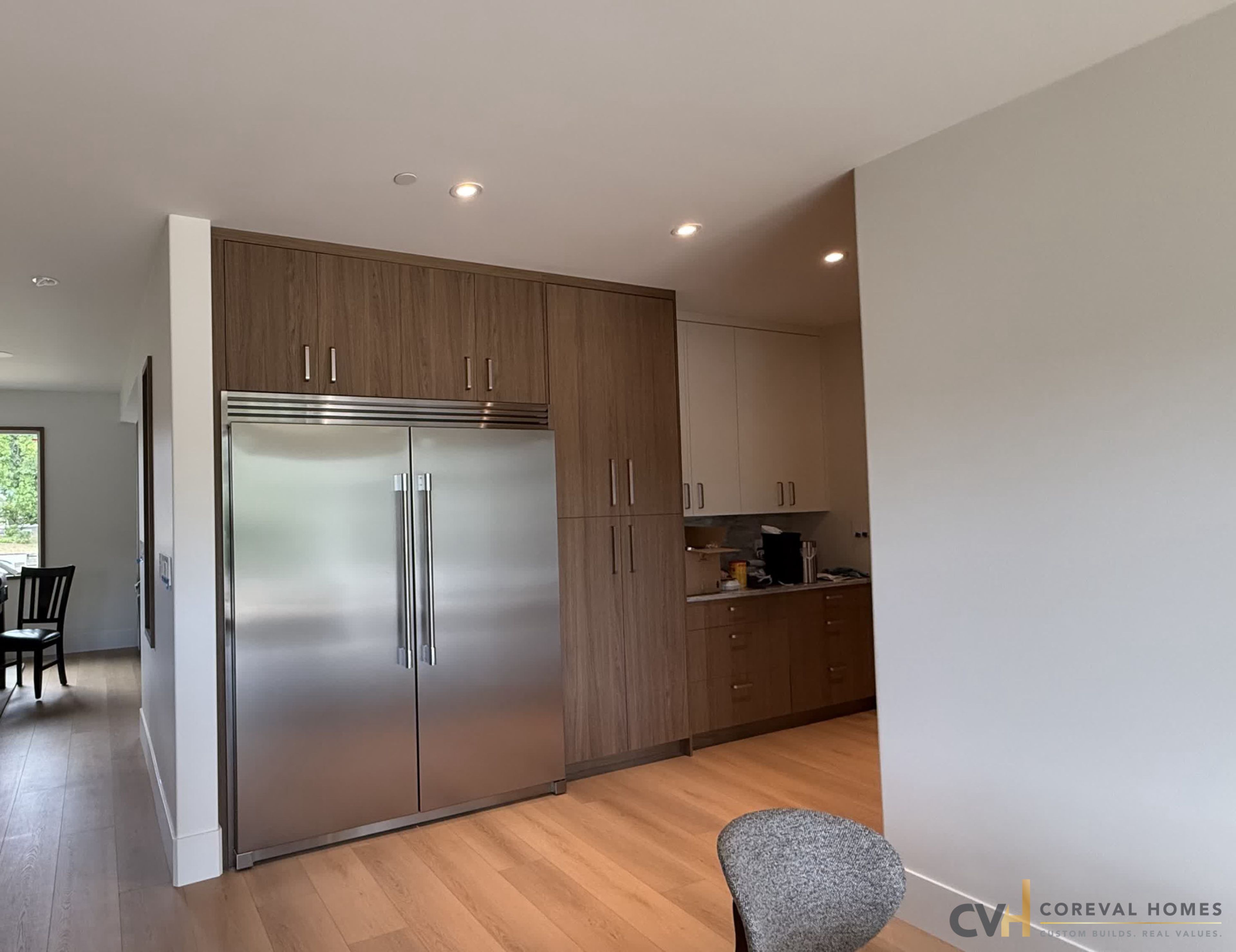Walnut millwork and integrated fridge wall in a completed CoreVal Homes kitchen