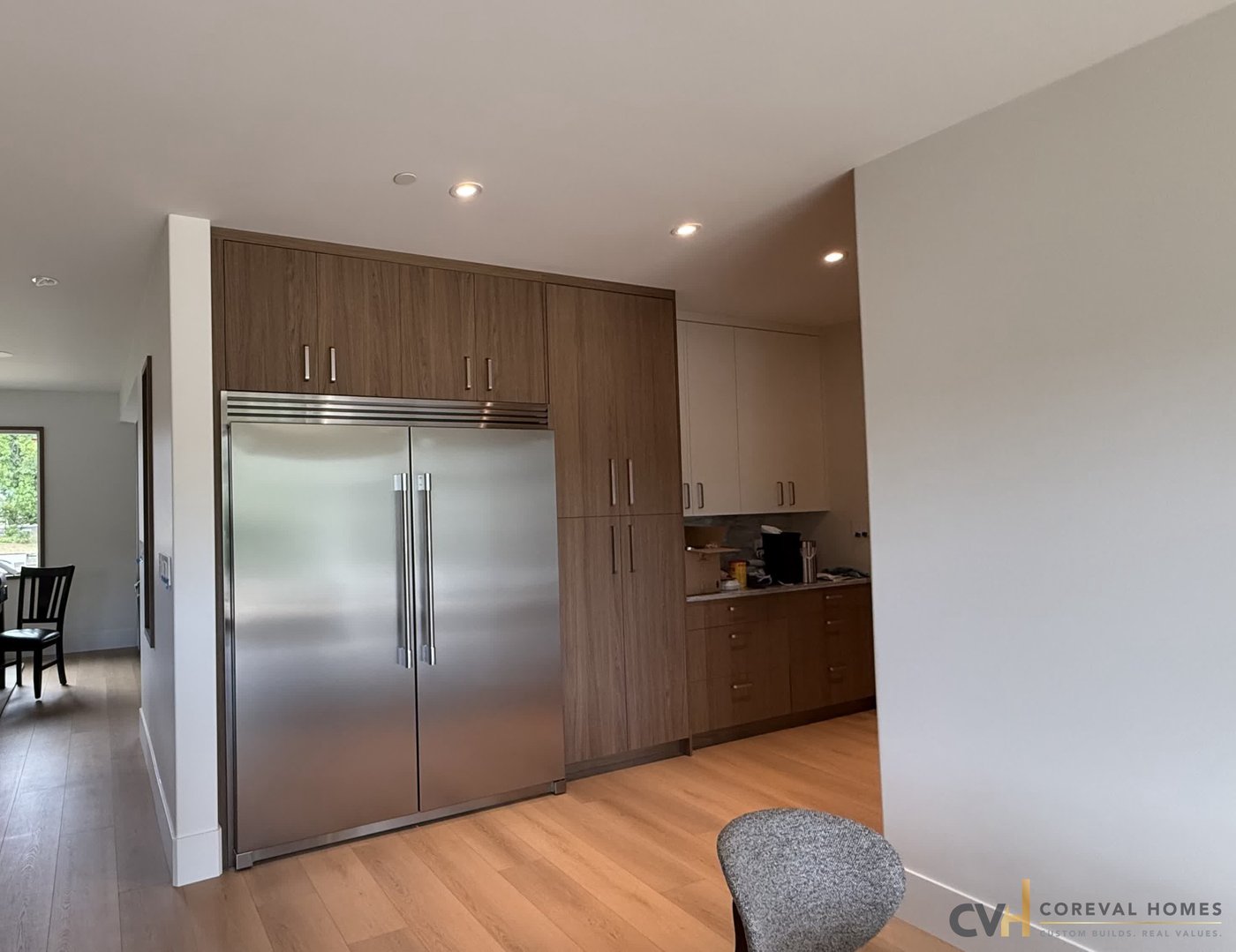 Walnut millwork and integrated fridge wall in a completed CoreVal Homes kitchen