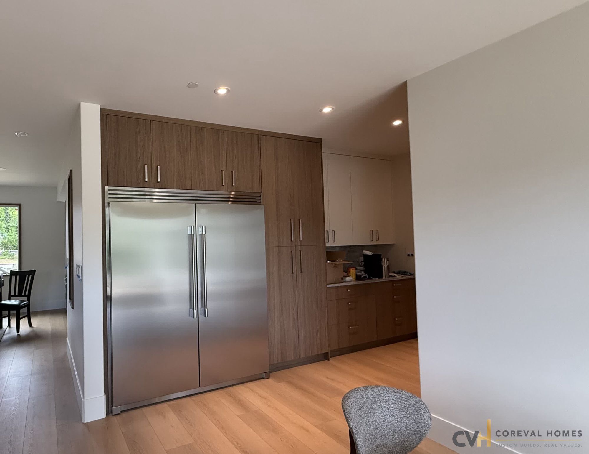 Walnut millwork and integrated fridge wall in a completed CoreVal Homes kitchen