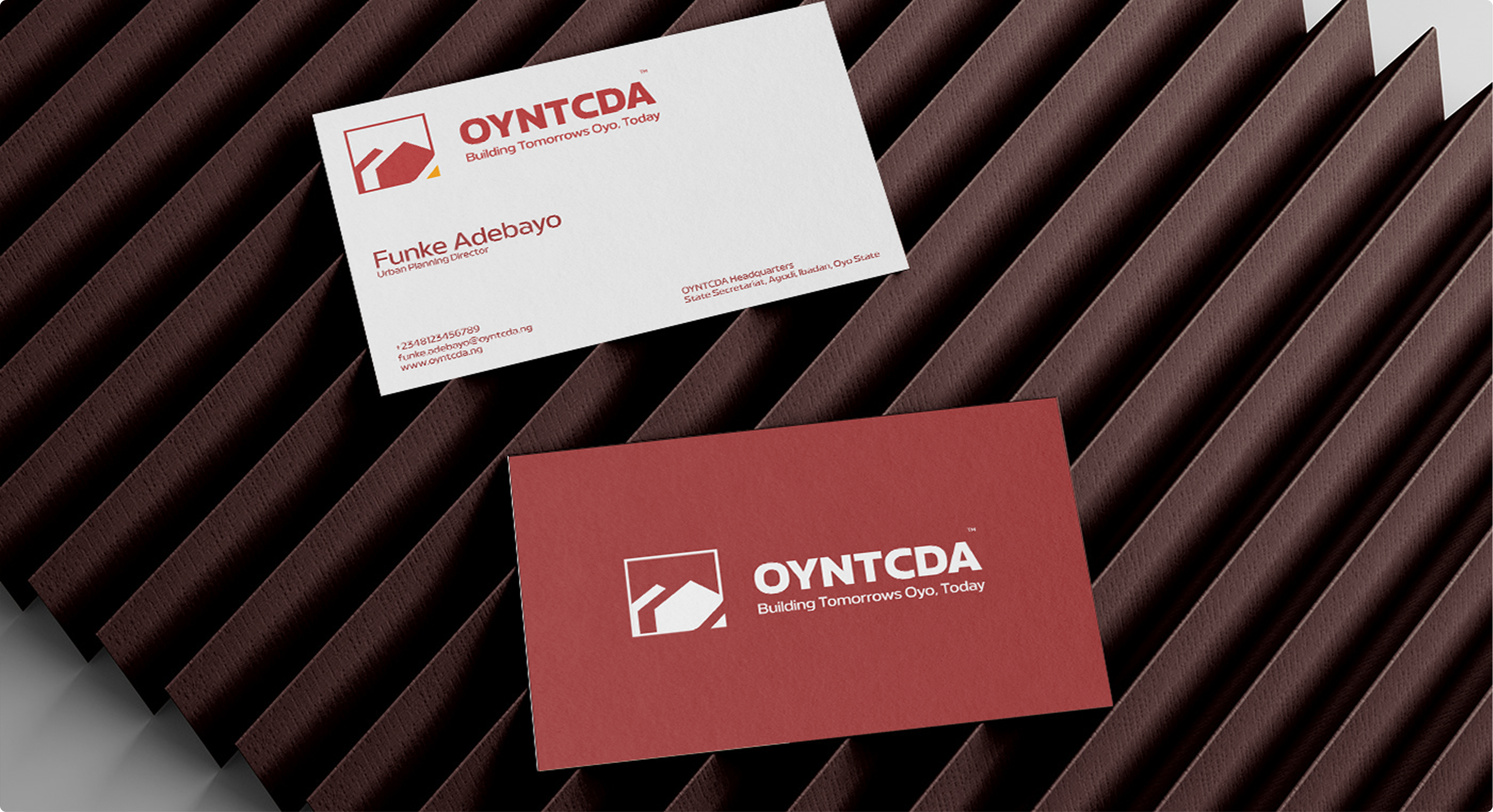 Red and white OYNTCDA business cards on a dark ridged surface