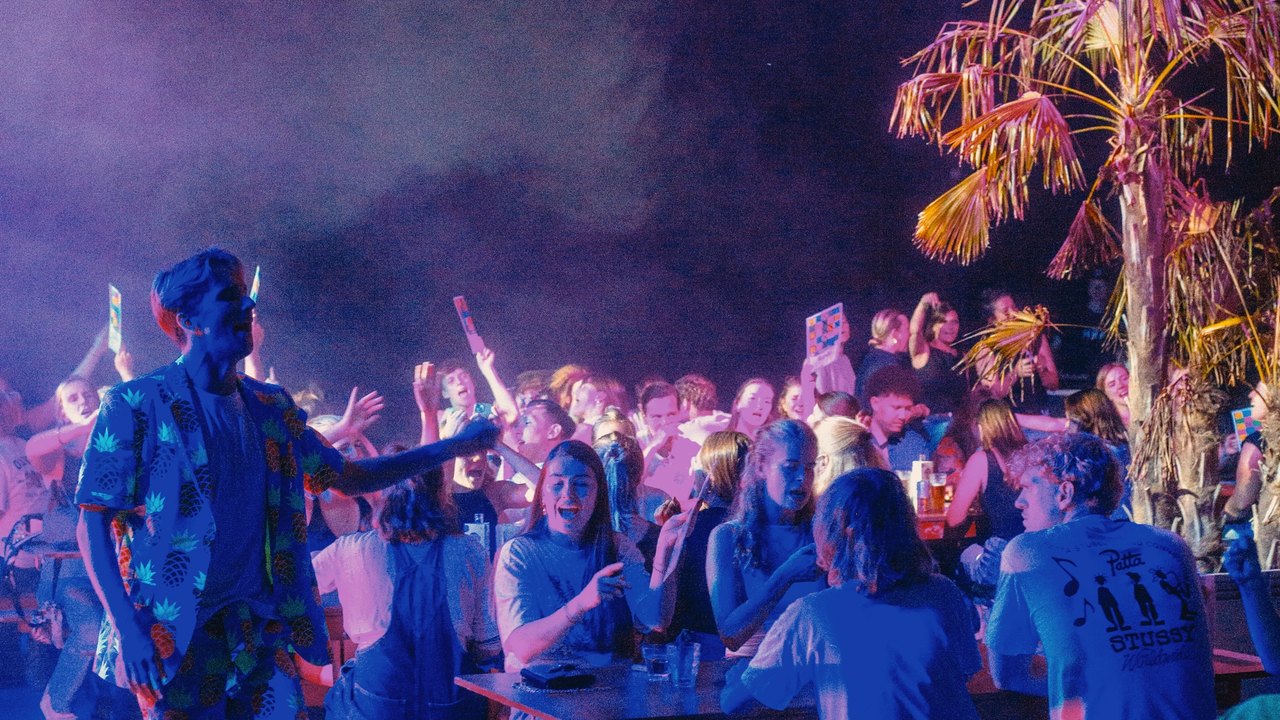 De host loopt tussen de teams tijdens Muziekbingo XXL.