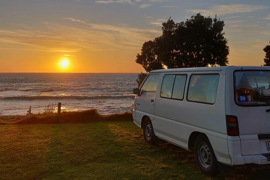 Camper bij zee tijdens zonsondergang