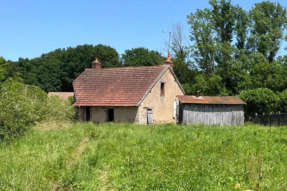 Stenen huis met rood dak in een groen veld in Frankrijk
