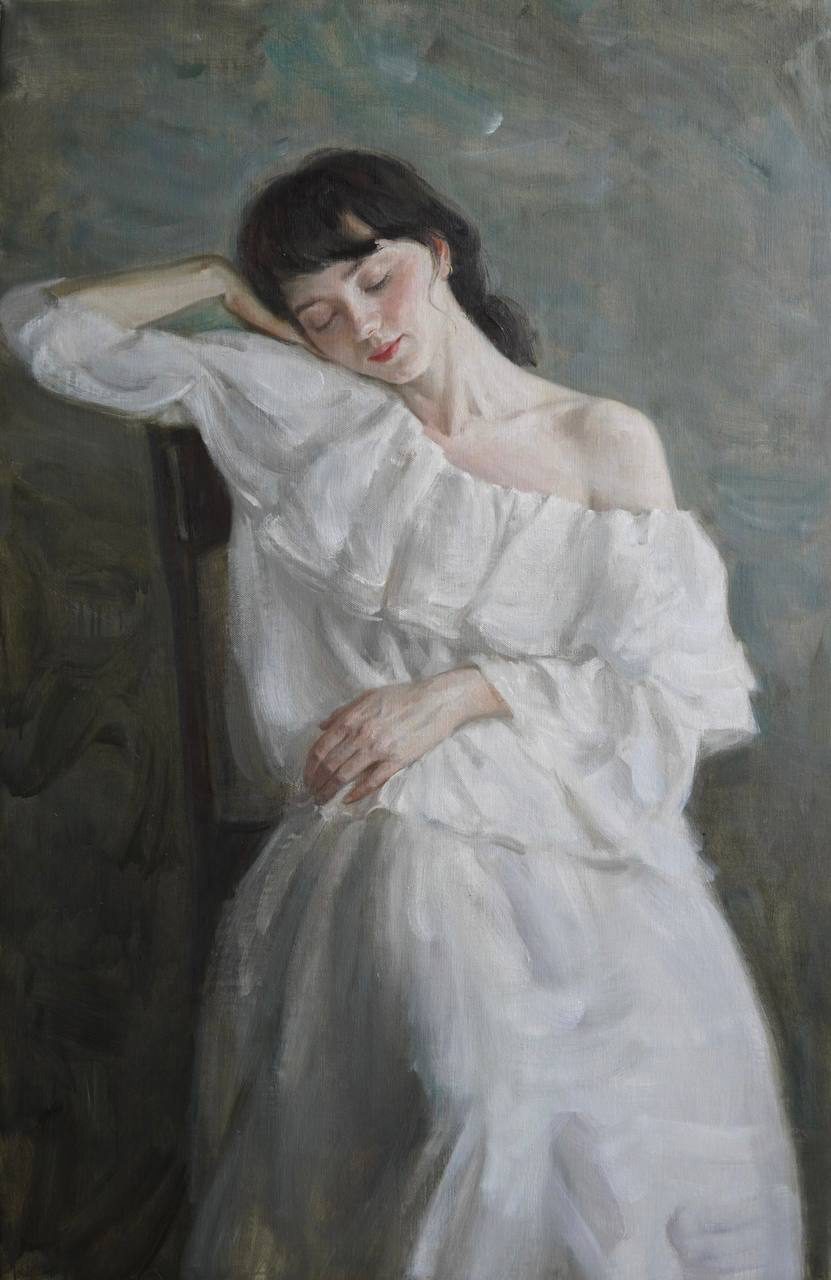 Woman in a white dress seated with her eyes closed against a muted green background.