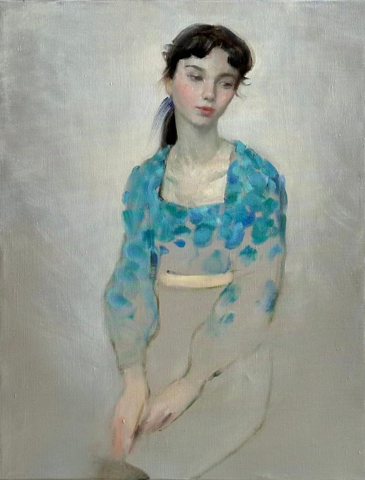 Portrait of a seated woman in a blue floral blouse and pale skirt.