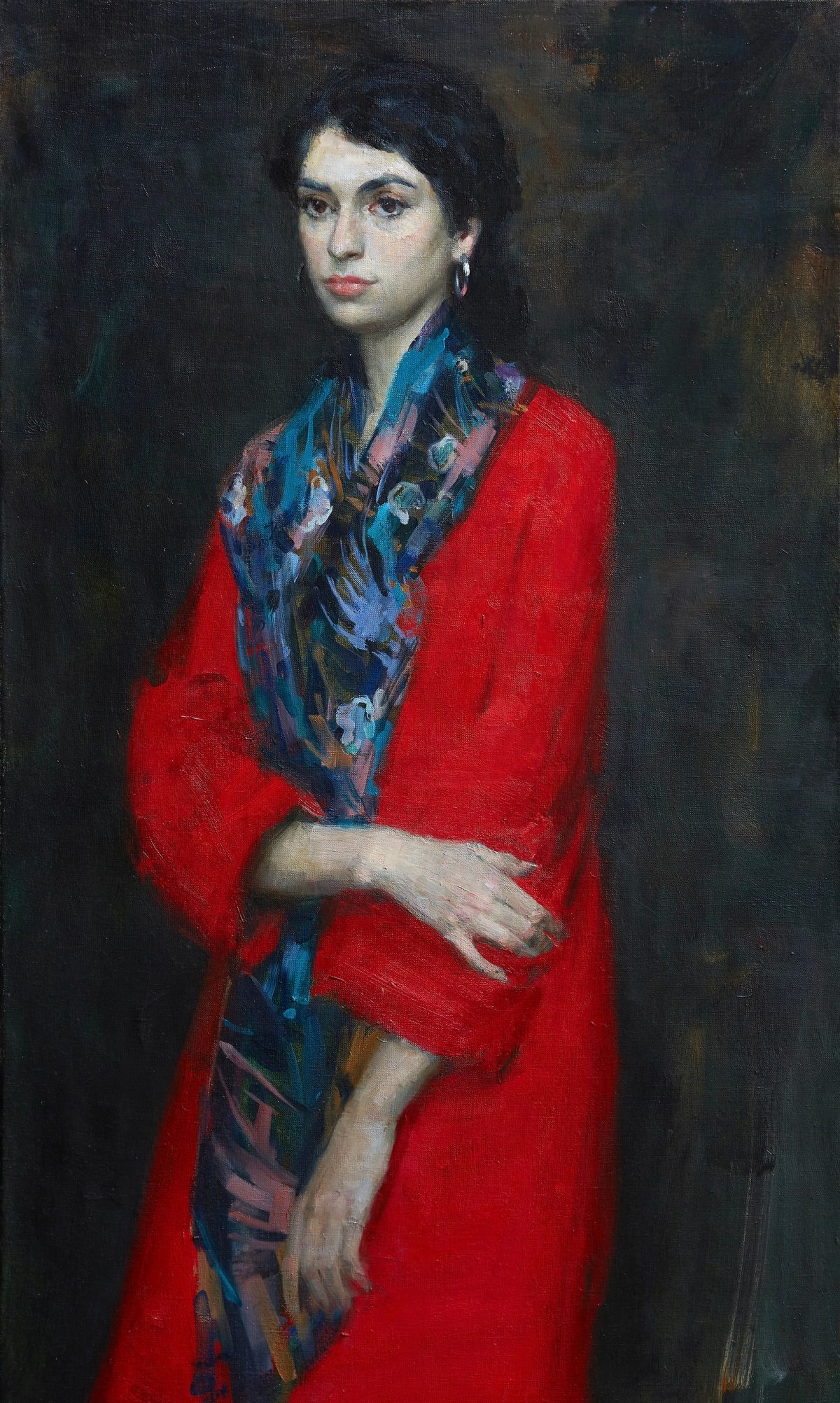 Portrait of a woman in a red coat and blue floral scarf against a dark background.