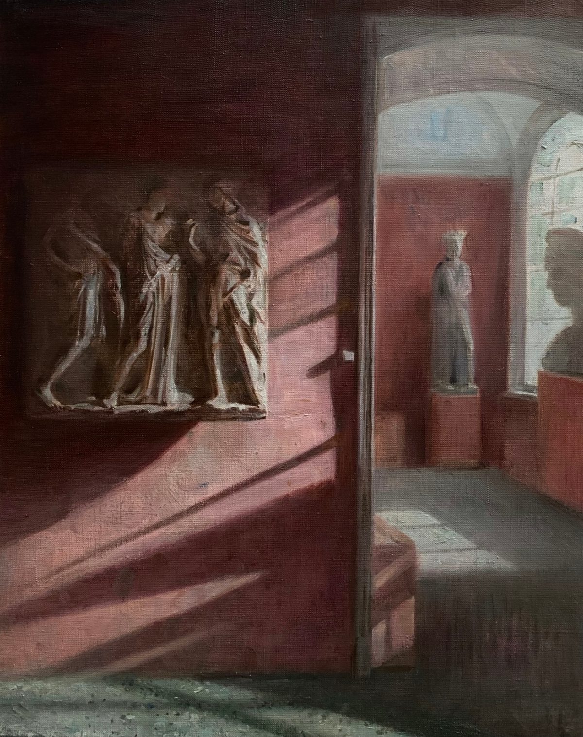 Museum interior with plaster sculptures in red-walled galleries and diagonal bands of light.