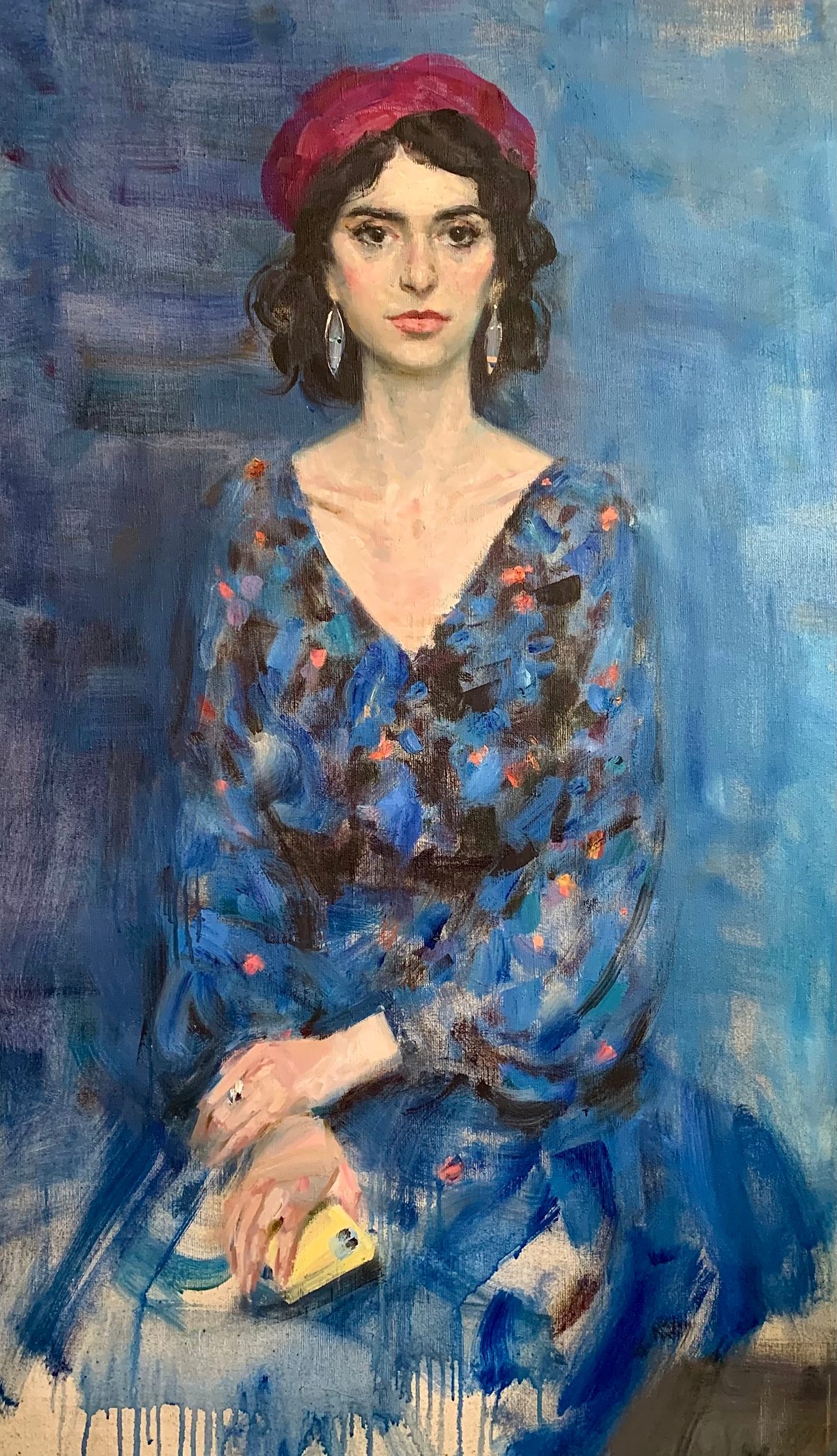 Portrait of a woman in a red beret and blue floral dress, holding a small yellow object.