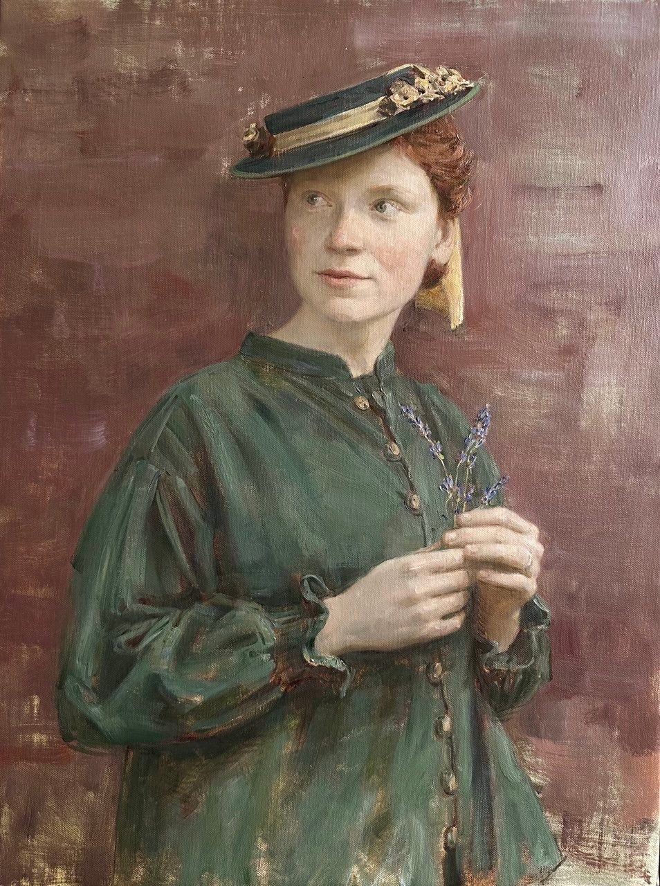 Portrait of a woman in a green dress and hat holding sprigs of lavender.