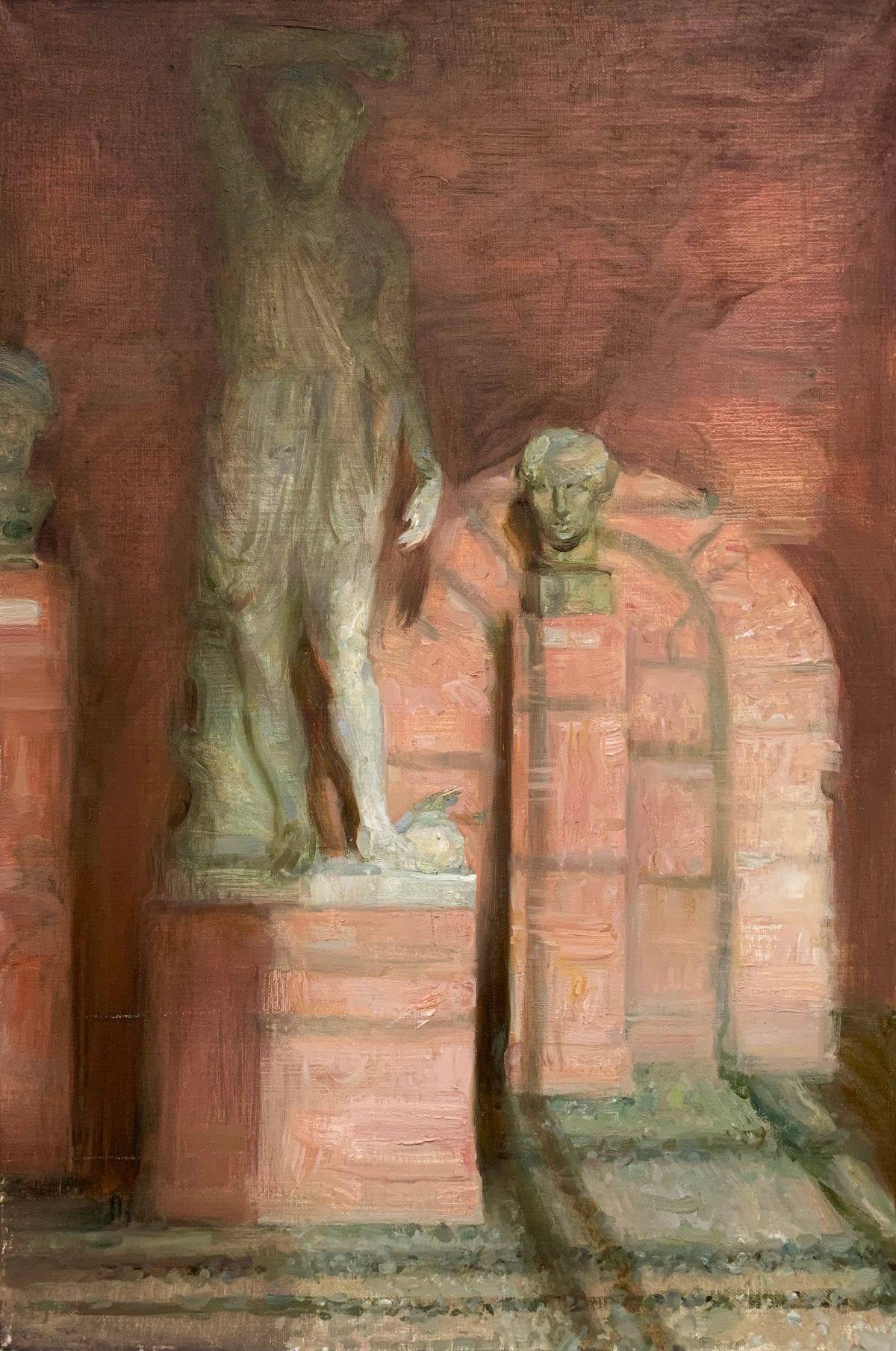 Classical statues and a bust in a pink-toned museum gallery.