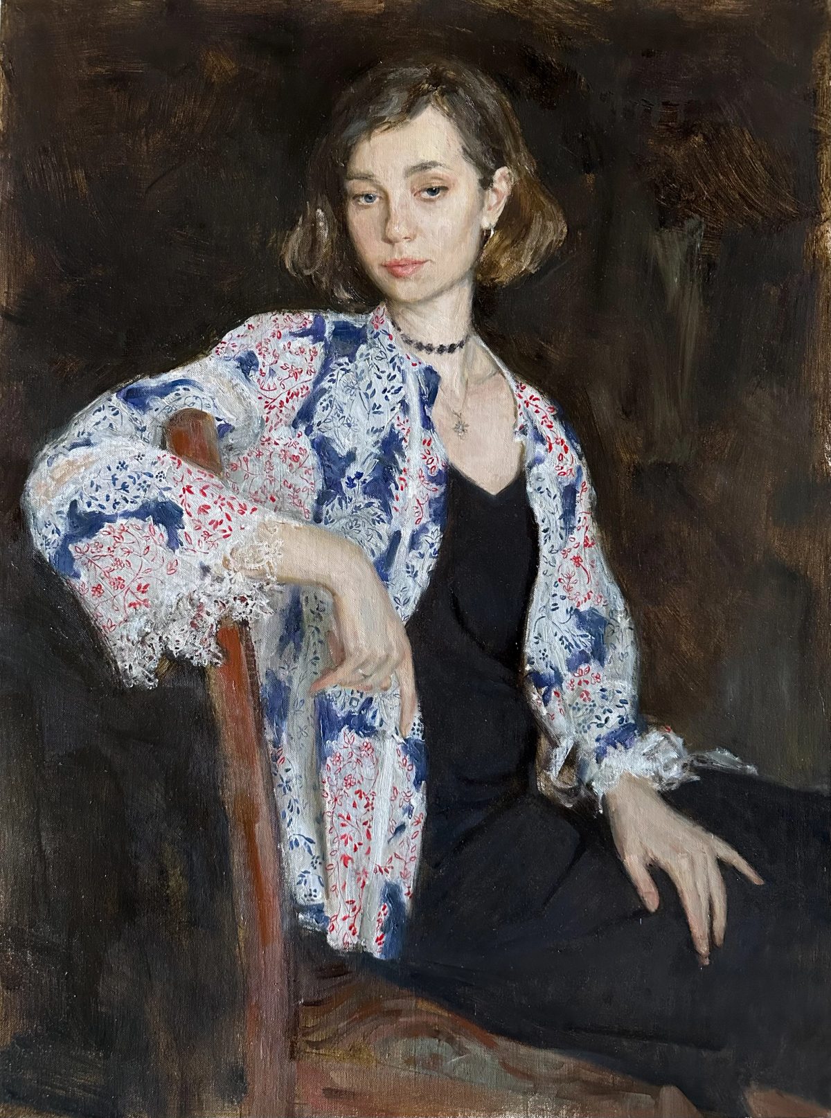 Portrait of a woman in a blue and white floral dress against a dark background.