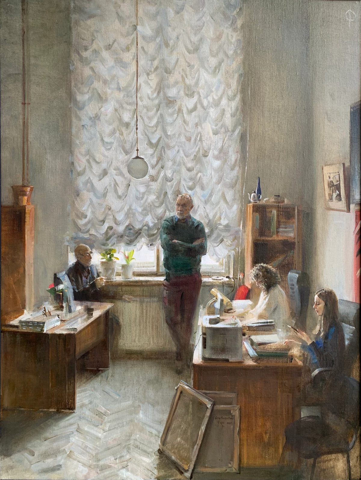 Office interior with four people at desks beneath a large lace-curtained window.