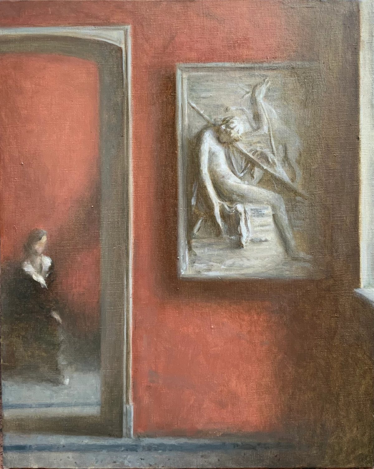 Woman in a dark dress looking at a framed figure painting in a red-walled gallery.