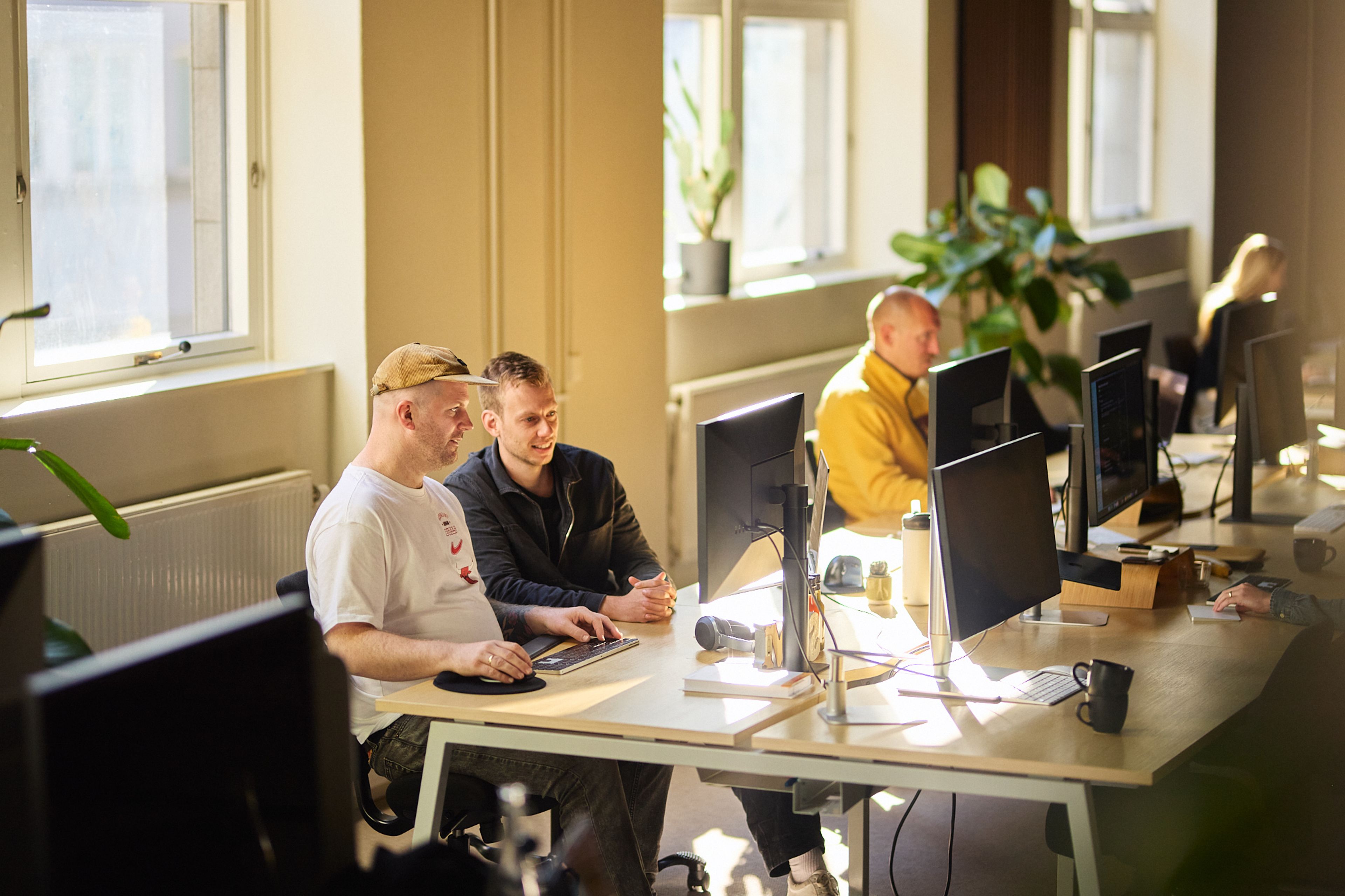 a group of people are sitting at desks in front of computer monitors in an office .