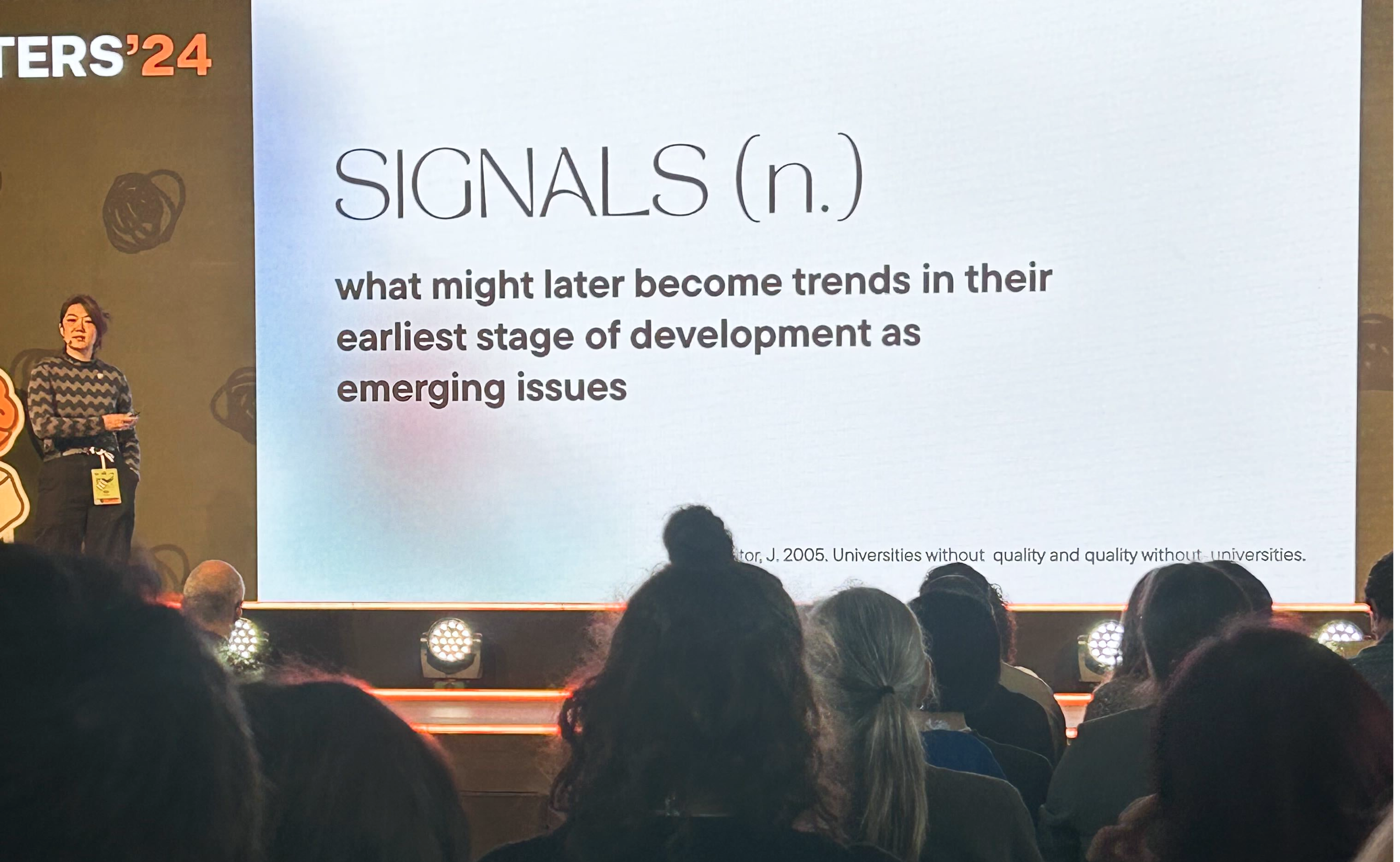 A woman stands in front of a screen that says signals