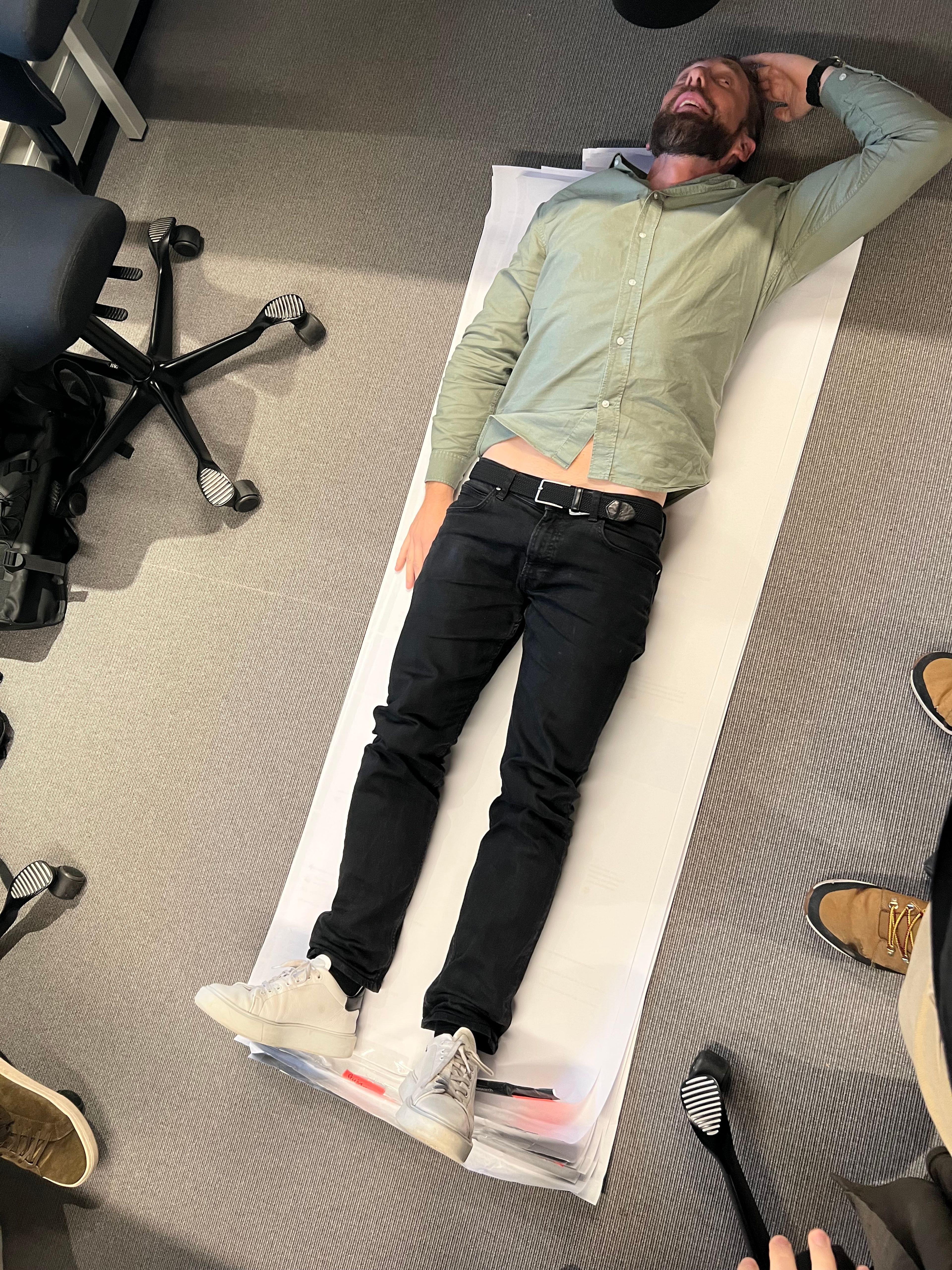 Greg in a green shirt is laying on the customer journey map on the floor