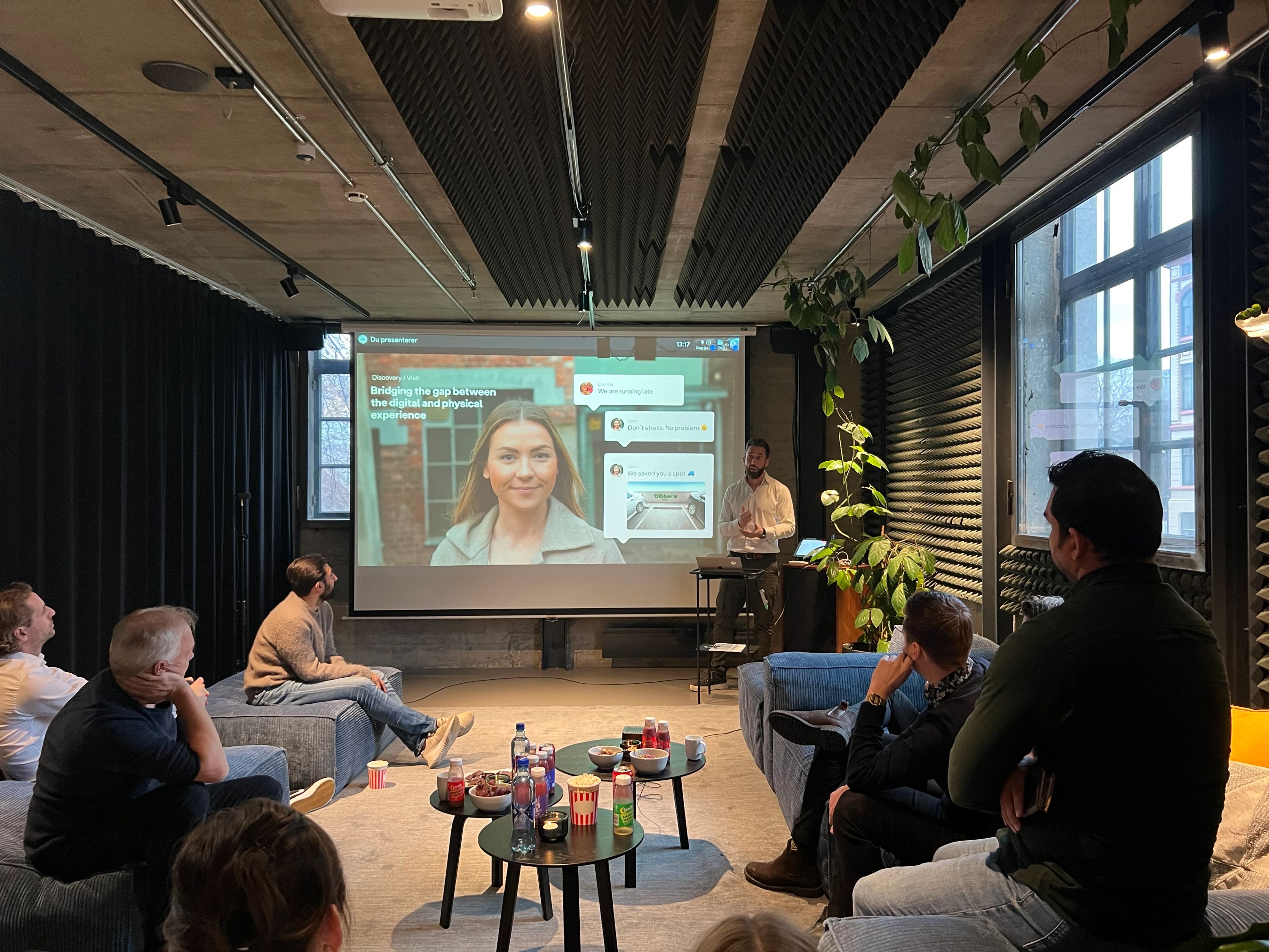 a group of people are sitting in a room watching a presentation on a projector screen