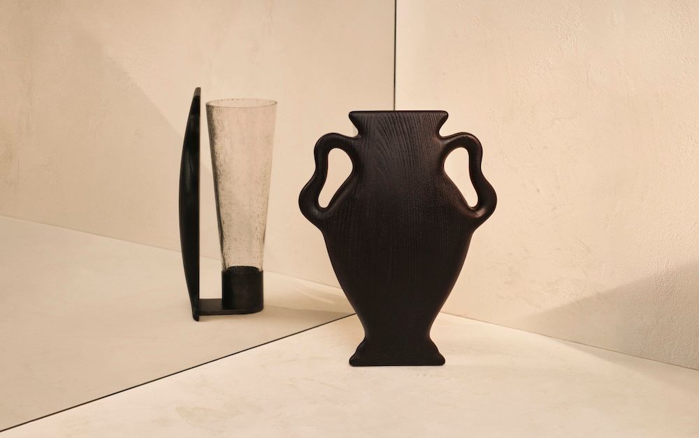 Black sculptural vase with its reflection in a mirror