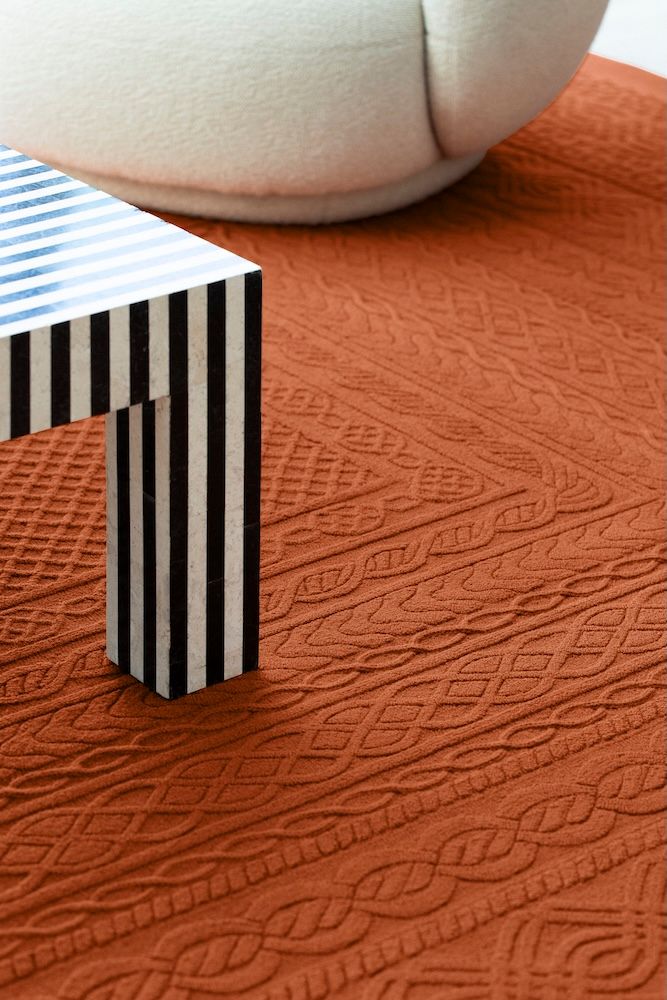 Copper coloured carpet with a striped black and white table by AB Concept and Tai Ping