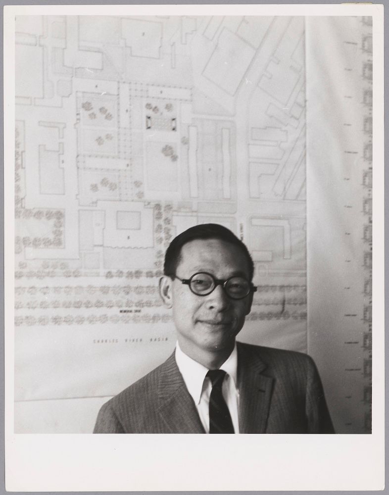 A man in glasses in a black and white photo with a drawing in the background