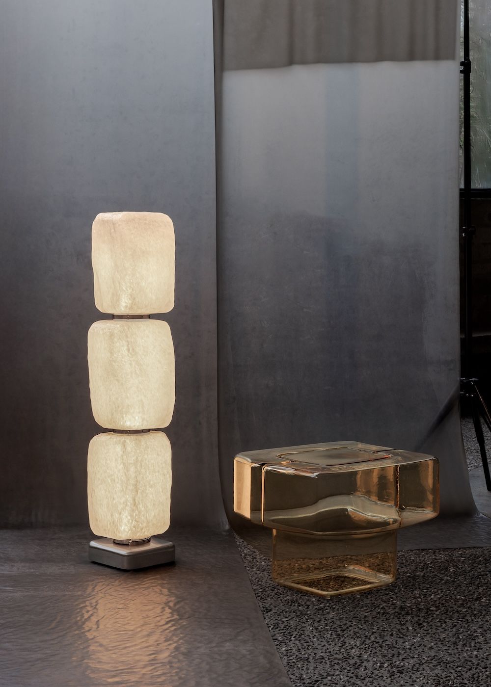 Illuminated cubed vertical floor lamp next to a glass side table 