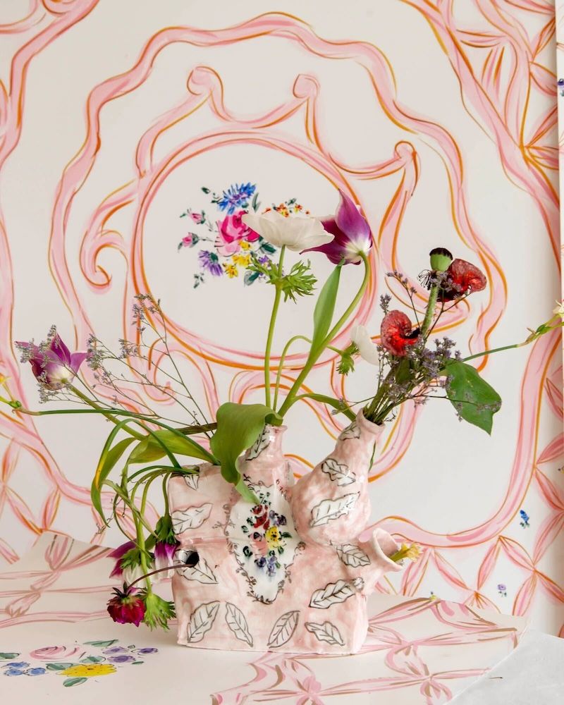 Florals in a vase with swirling pink design in backdrop from lattice collection by Calico Wallpaper