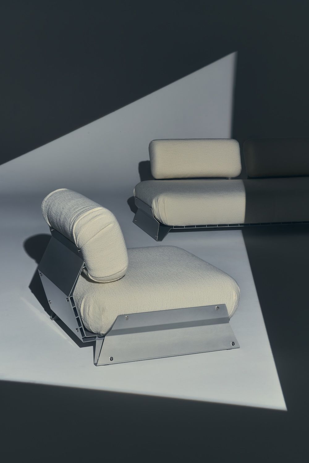 Cream chairs shown at an angle with strong, shadowy lighting