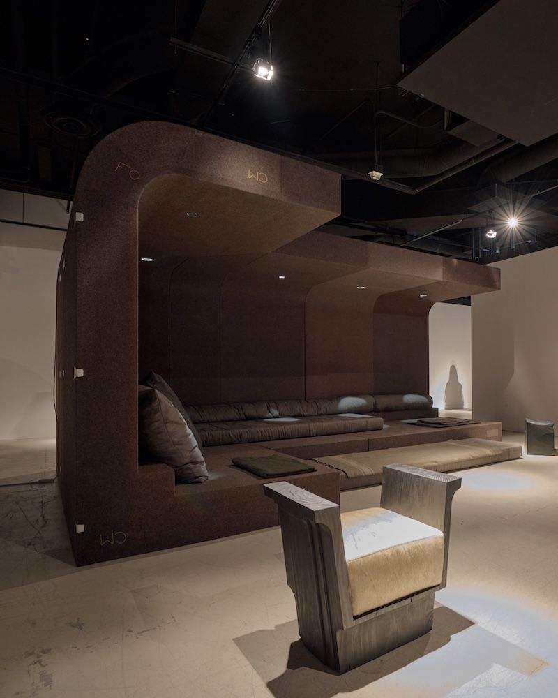 Brown seating area in an exhibition setting with spotlights 
