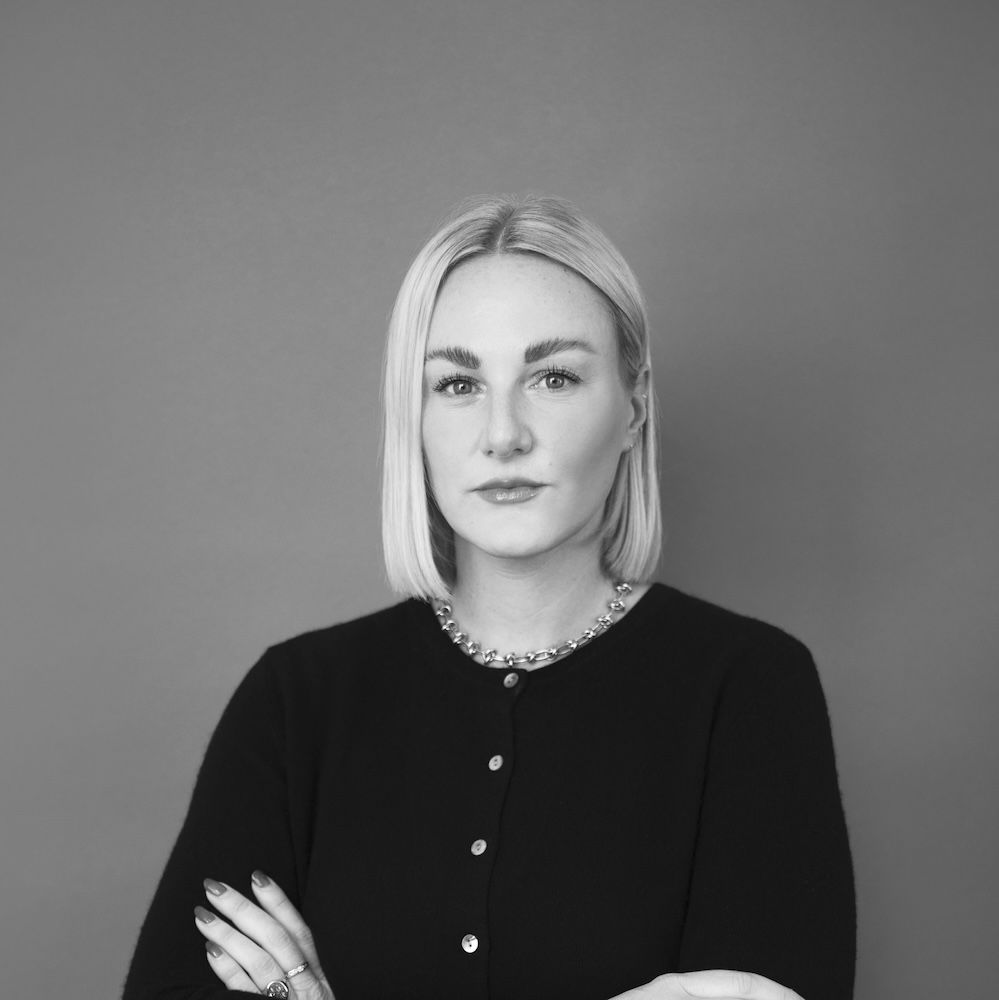 A black and white image of a woman with her arms crossed - Cameron Flaherty of the Camron Office in New York