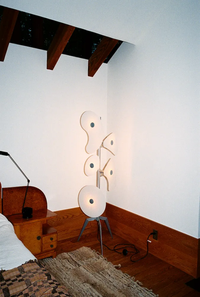 A floor light with wooden shelving and wooden features across the room 