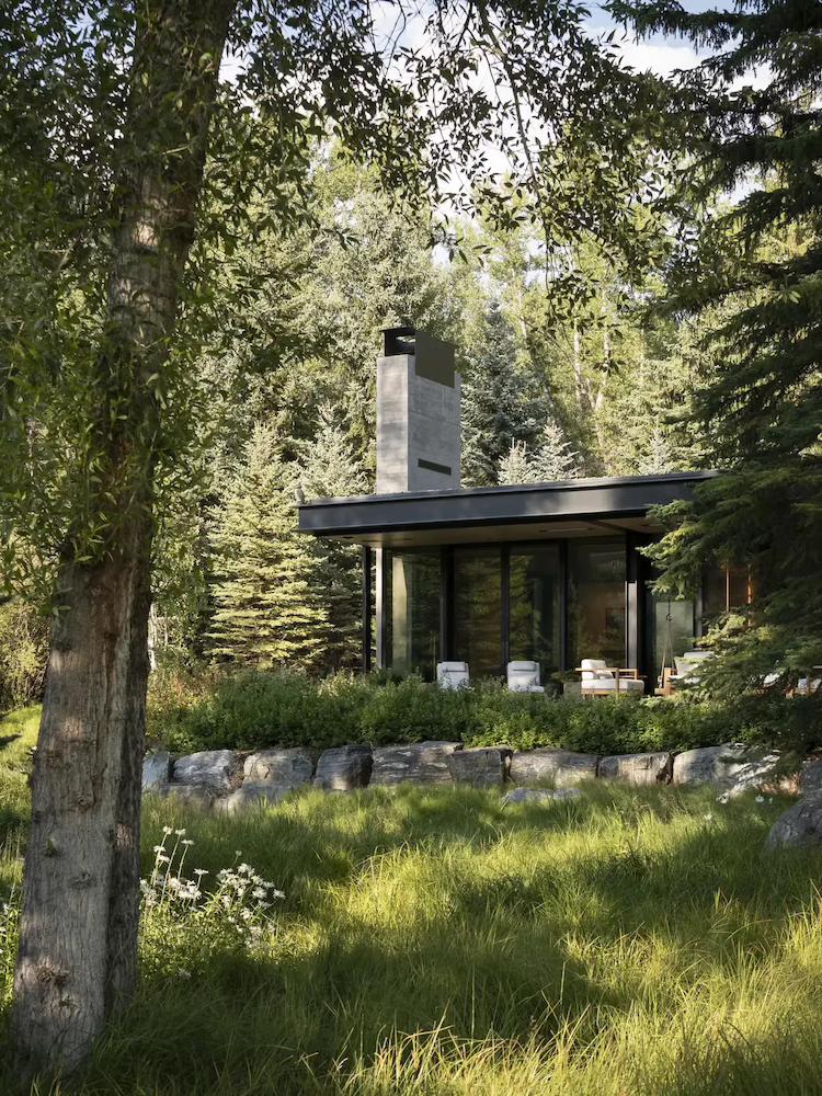Image of house nestled within the greenerry with grass in foreground and trees
